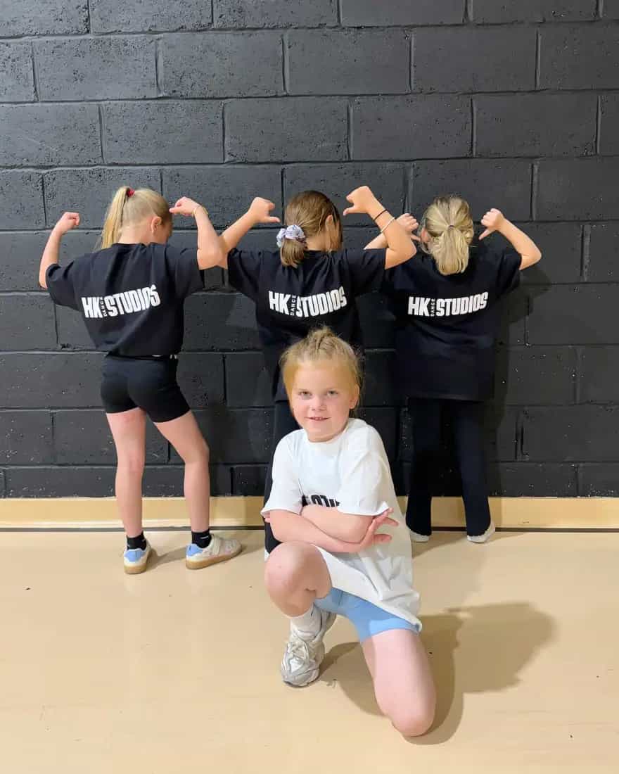Four HK Dance Studios kids showing off their kit with one dancer crouching in front