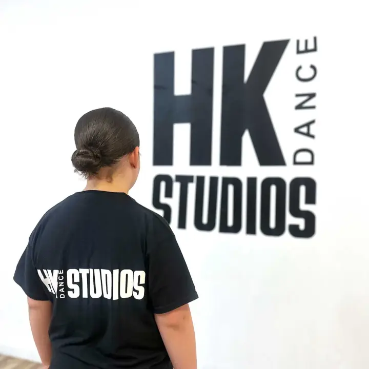 Dancer in HK Dance Studios kit facing the studio wall logo at Billericay HQ